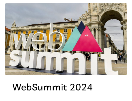Large white 3D letters spelling 'web summit' with colorful triangular shapes in the middle, set outdoors in front of a historic arch.